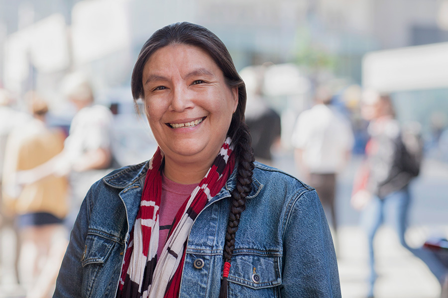 Native American woman stands smiling on a city street