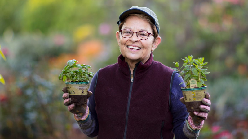 A woman holding a plant in each hand.